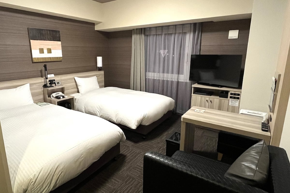 Una habitación de hotel con dos camas, un televisor, un escritorio y una silla.