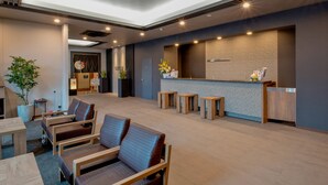 Een ruime lobby met zithoeken, een receptiebalie en een groot raam.