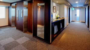 Een hotelgang met houten lambrisering, een receptiebalie en een lift.