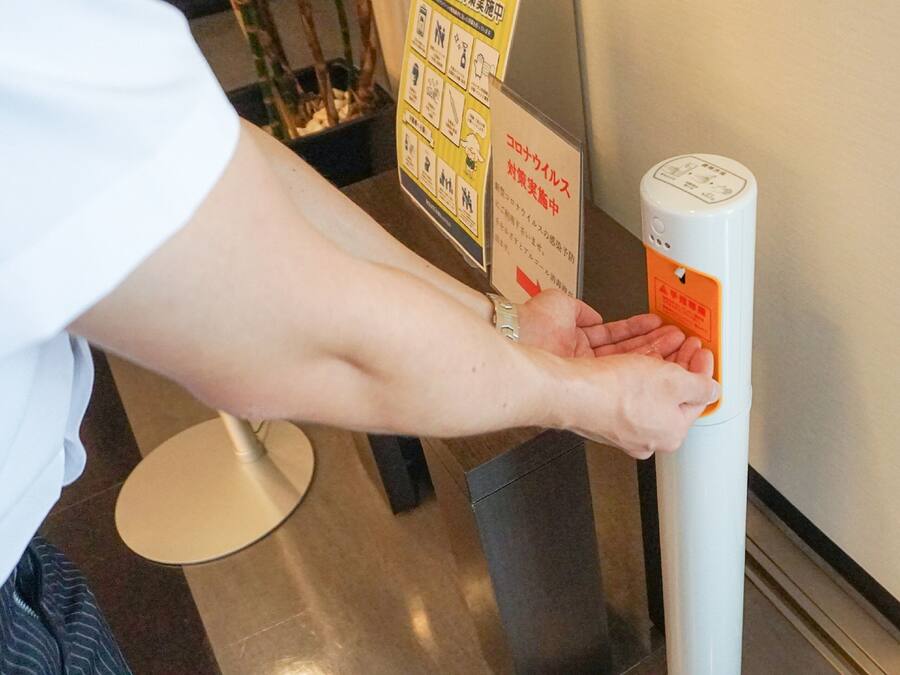 Una persona usando un dispensador de gel hidroalcohólico.