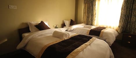 A hotel room with two beds, a nightstand, and a window with curtains.