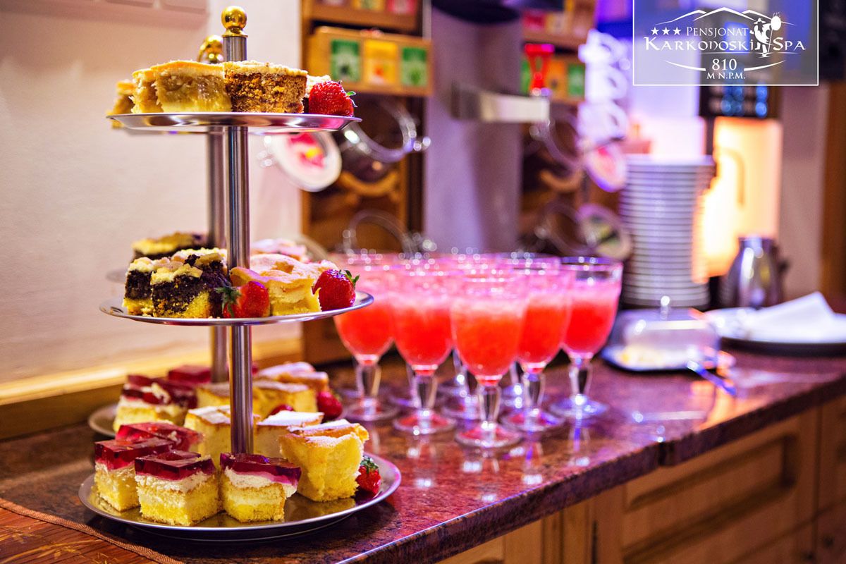 Ein dreistöckiges Kuchenbuffet mit verschiedenen Backwaren und einer Auswahl an roten Getränken an einer Bar.