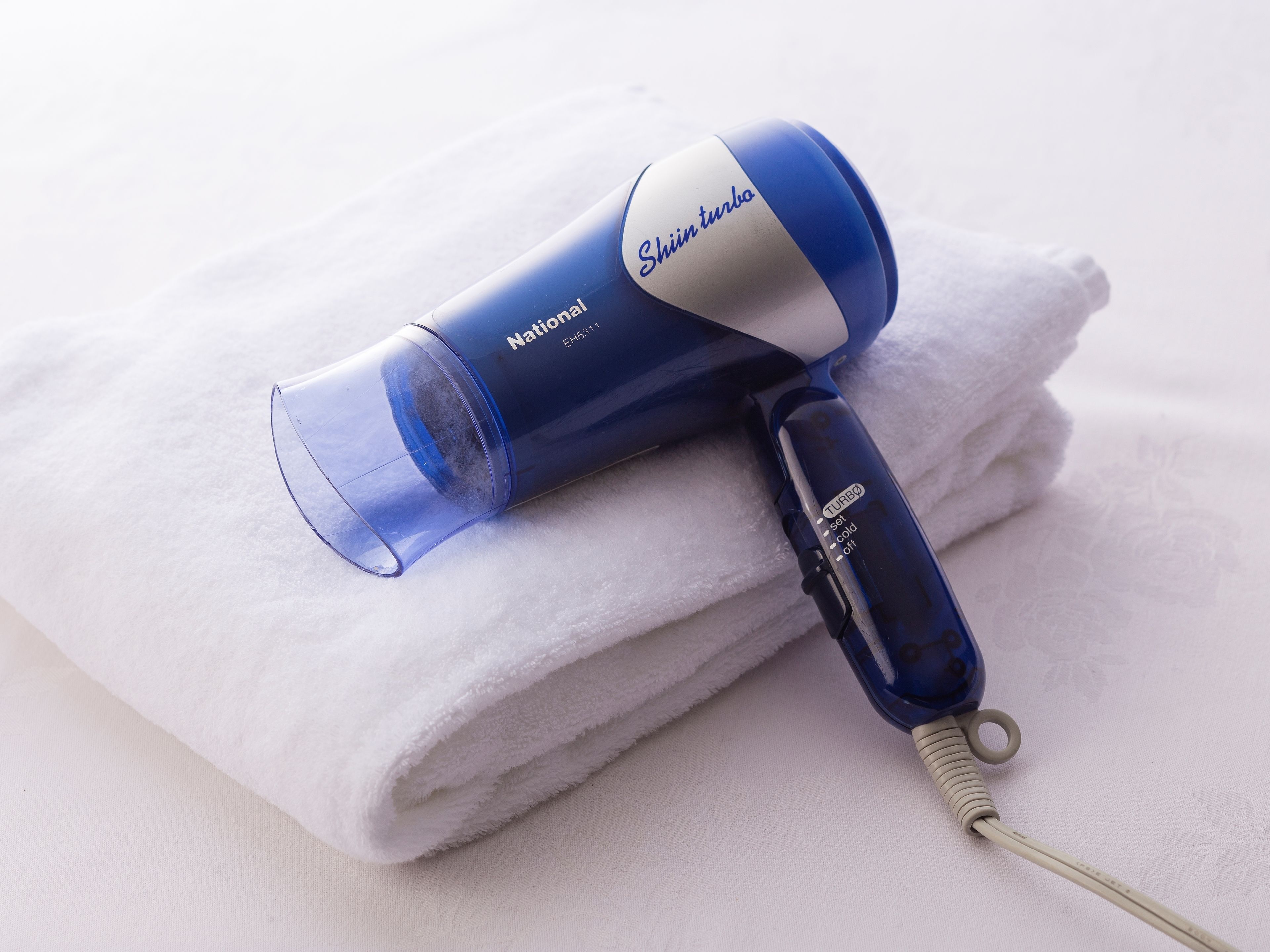 A blue portable hair dryer with a clear nozzle, labeled "Shin turbo," and a control switch with settings.
