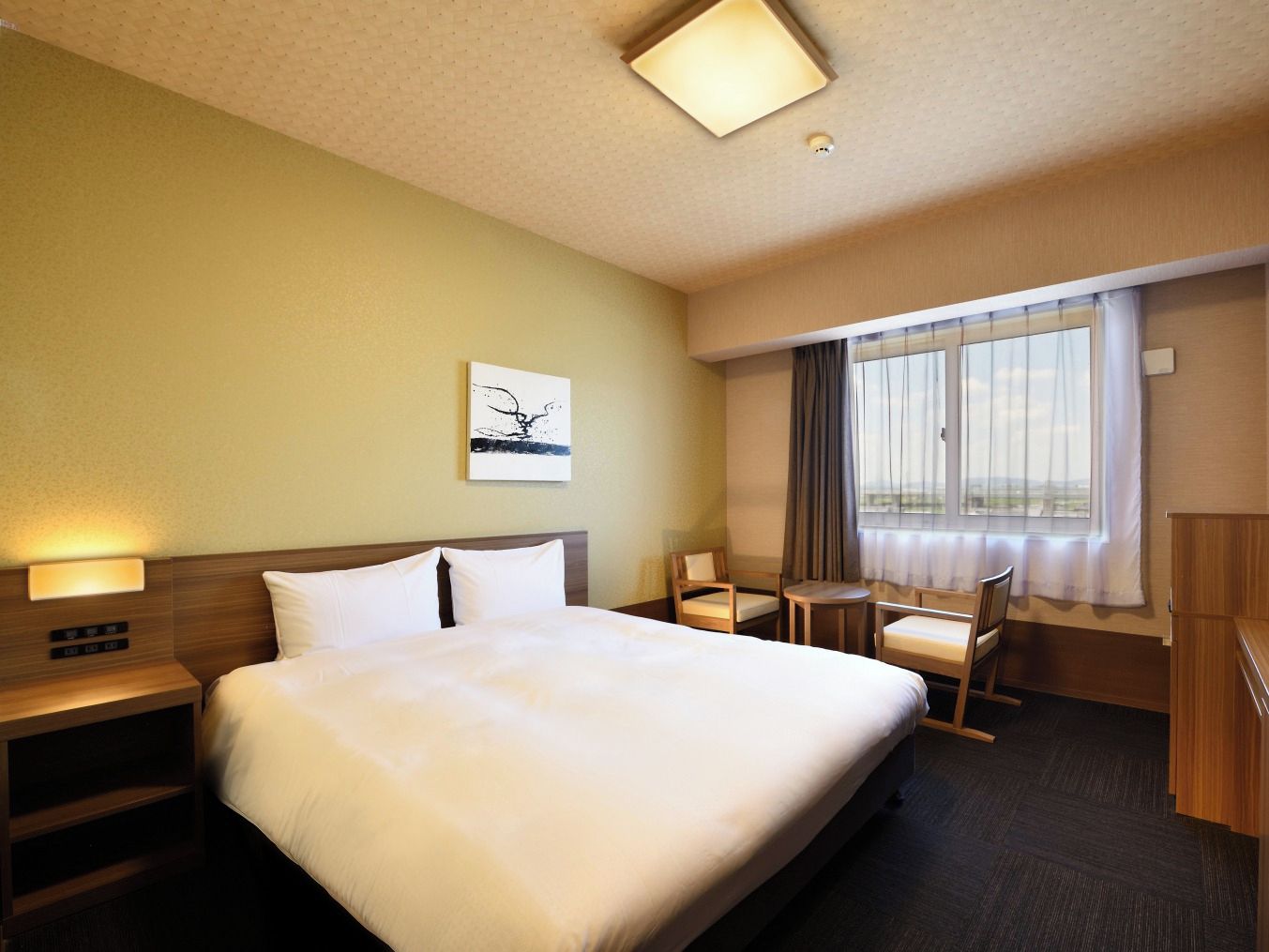 A hotel room with a large bed, bedside tables, a desk, and a chair.