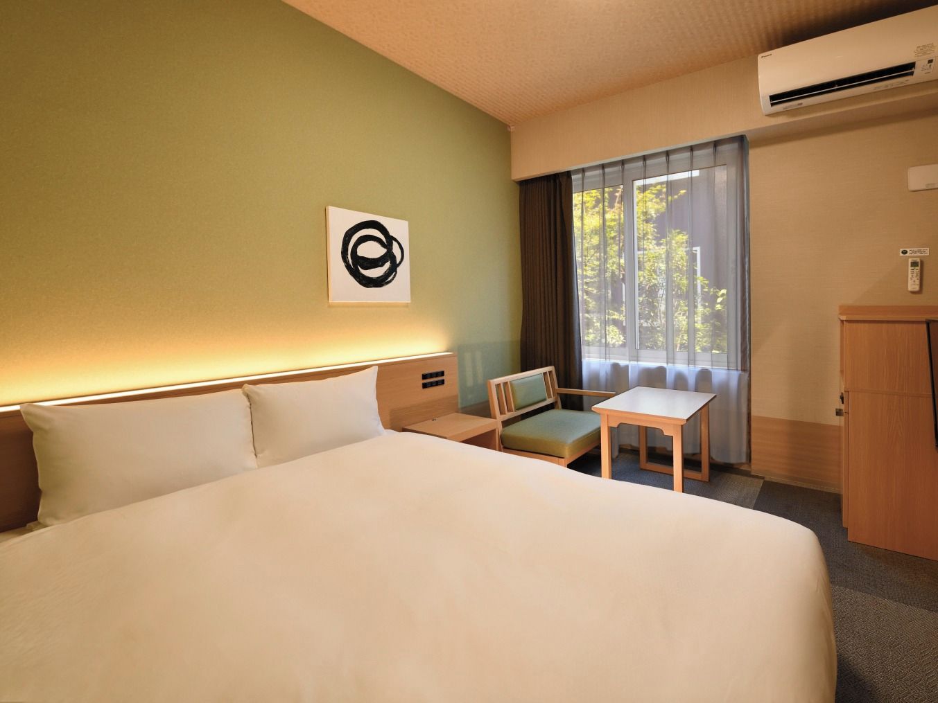 A hotel room with a large bed, a desk, a chair, and a window with curtains.