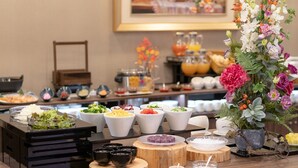 A buffet setup with various food items and a floral centerpiece. - Grandvrio Hotel Nara Wakura (Tenri)