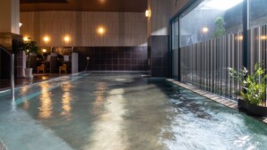 A modern indoor pool area with a wet floor, wooden panel walls, and a seating area with stools. - Grandvrio Hotel Nara Wakura (Tenri)
