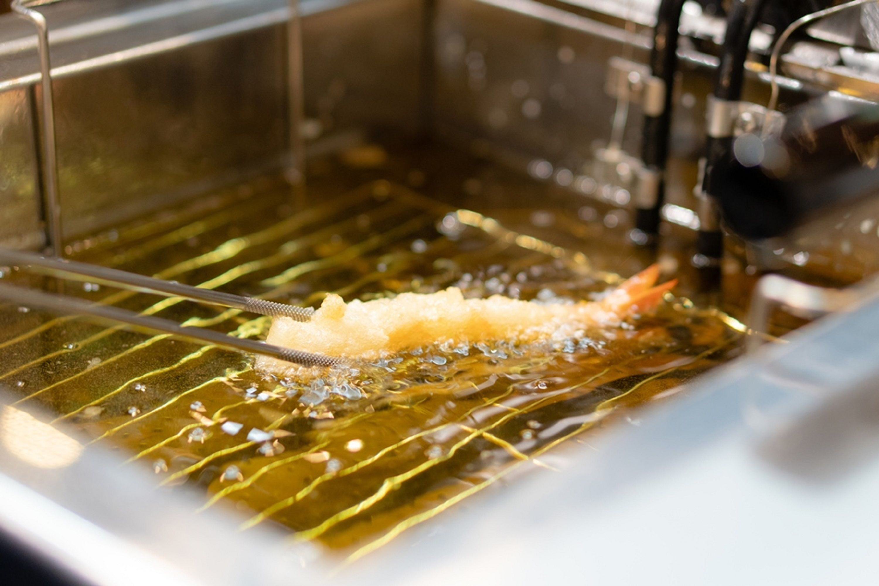 A deep fryer with oil and a piece of food being fried.