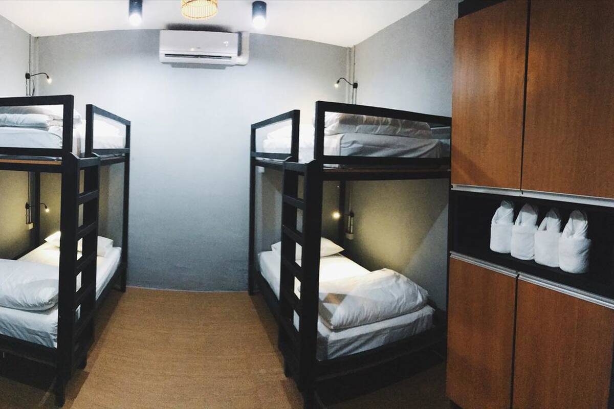 A bunk room with two bunk beds, a wooden wardrobe, and a carpeted floor.