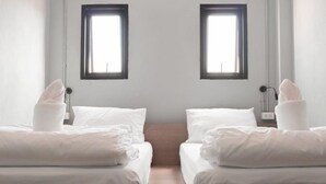 A hotel room with two beds, a wooden floor, and two windows with black frames. - Bedbox Vientiane Hostel (Vientiane)