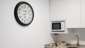 A modern kitchen with white cabinets, a microwave, and a dining area with a table set for two. - APARTMENT 1 MENCIA (MIRADORES DEL ISASA) (Herce)