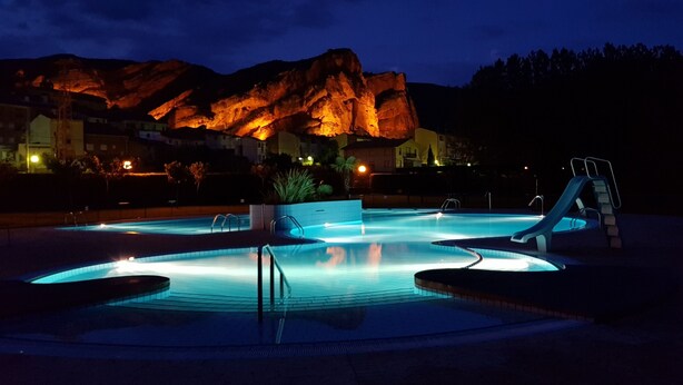 A swimming pool with a slide, surrounded by buildings and a mountain in the background. - APARTMENT 1 MENCIA (MIRADORES DEL ISASA) (Herce)