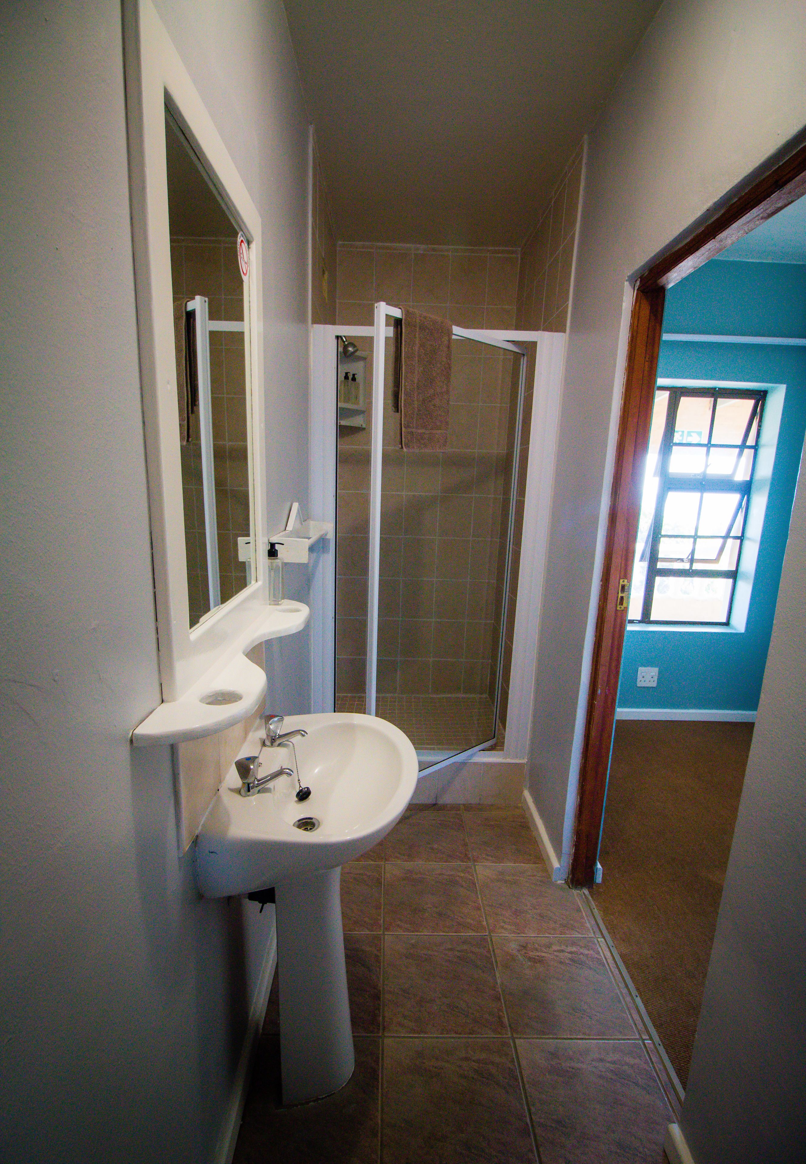 A bathroom with a sink, mirror, and shower.