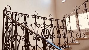 A staircase with ornate black metal railings and a beige wall.