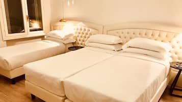 Ein Hotelzimmer mit einem großen Bett, zwei kleineren Betten, einem Nachttisch und einem Fenster.