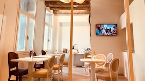 A dining area with wooden beams, white walls, and a TV on the wall.