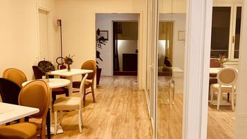 A modern dining area with wooden flooring, white walls, and a glass partition.