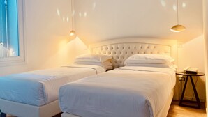 Une chambre d’hôtel avec deux lits, une table de chevet avec une lampe et une fenêtre.