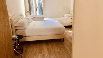 A room with a large bed, a sofa, and a small table with a phone.