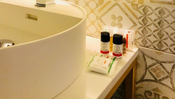 Une salle de bain avec un grand lavabo blanc, un miroir et des carreaux muraux à motifs.