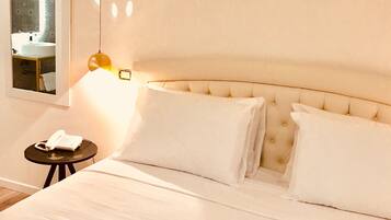 A hotel room with a bed, a bedside table with a lamp, and a mirror on the wall.