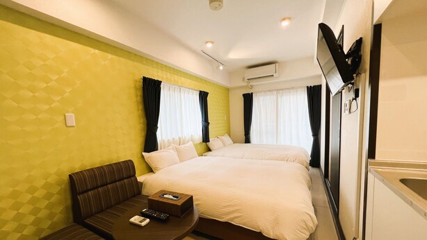 Ein Hotelzimmer mit einem großen Bett, einer Couch, einem kleinen Tisch und einem an der Wand befestigten Fernseher.