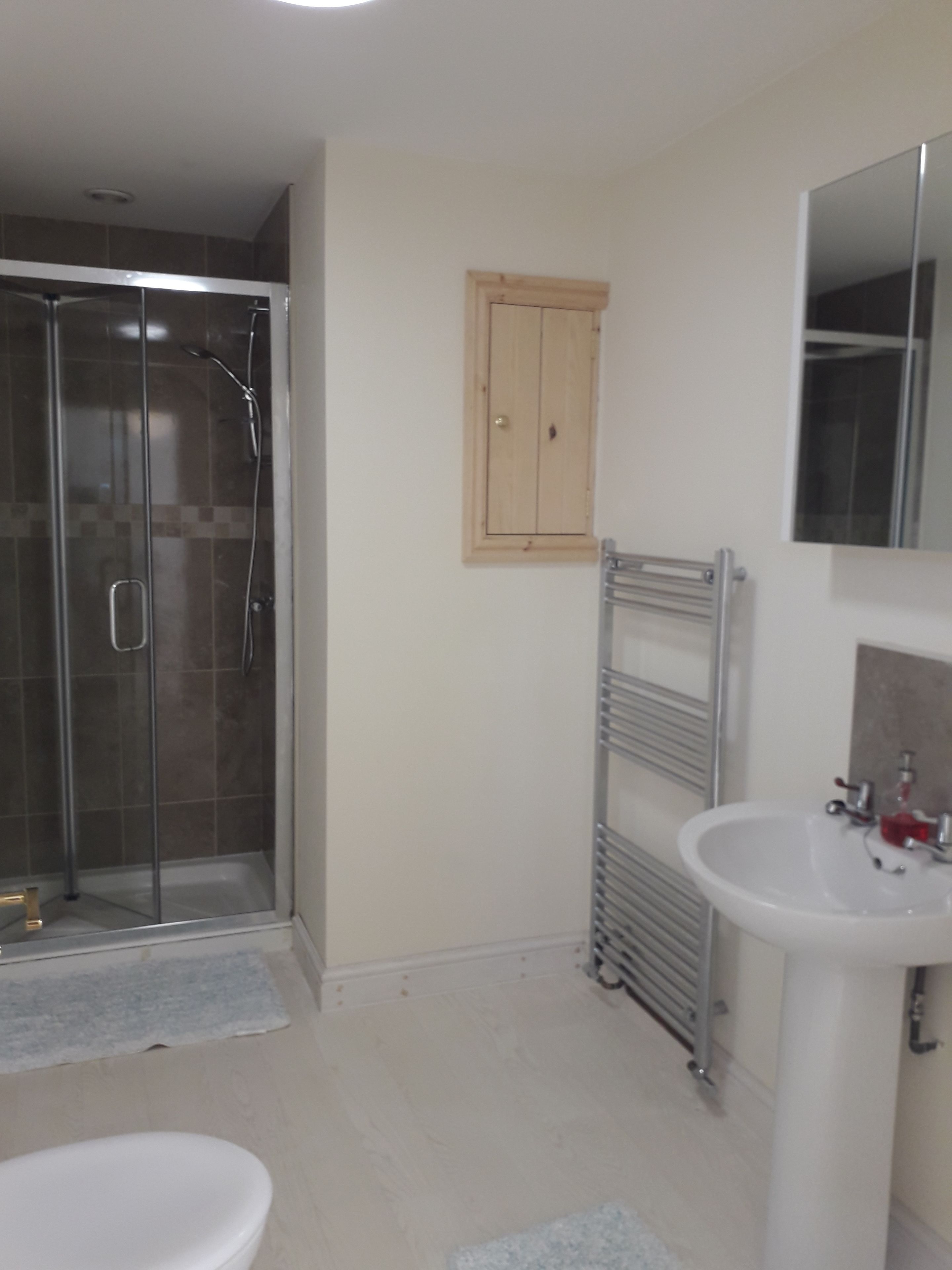Un baño con cabina de ducha de vidrio, un lavabo blanco y un mueble de madera.