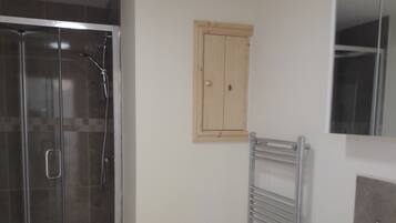 Un baño con cabina de ducha de vidrio, un lavabo blanco y un mueble de madera.