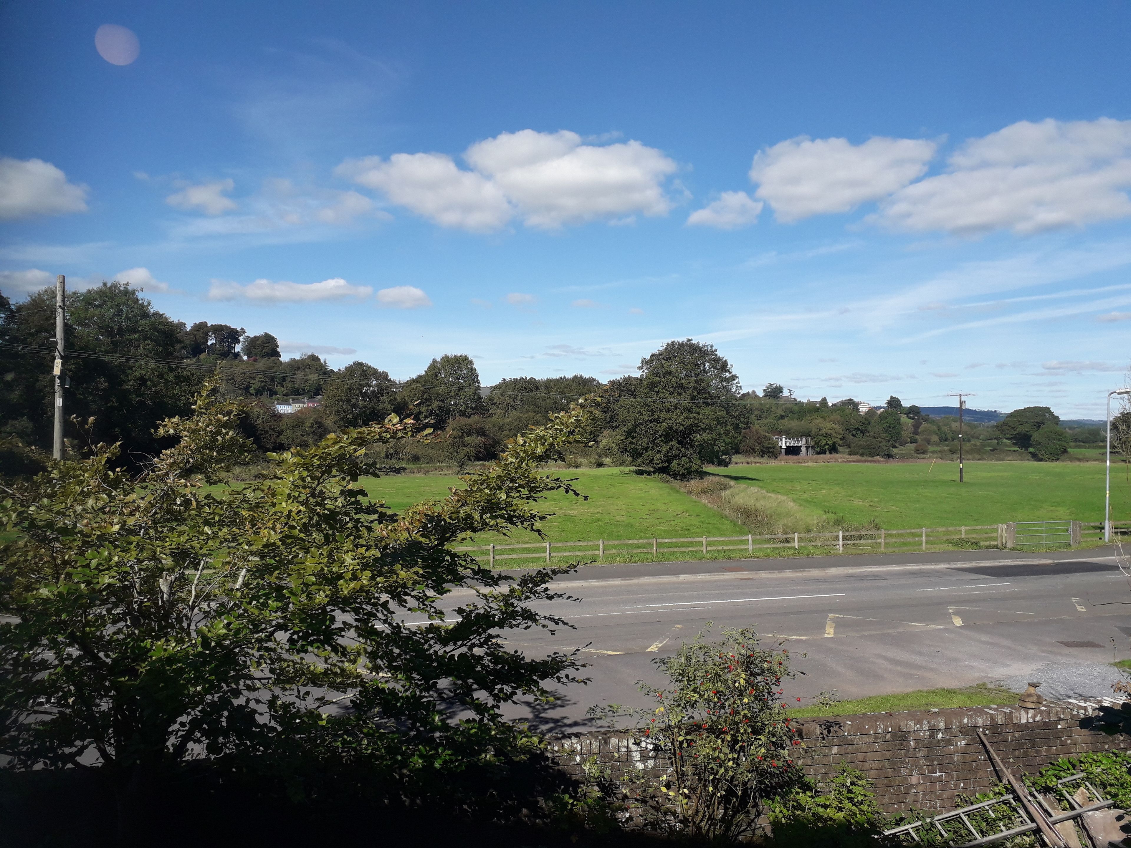 A parking lot with a grassy field and trees in the background.