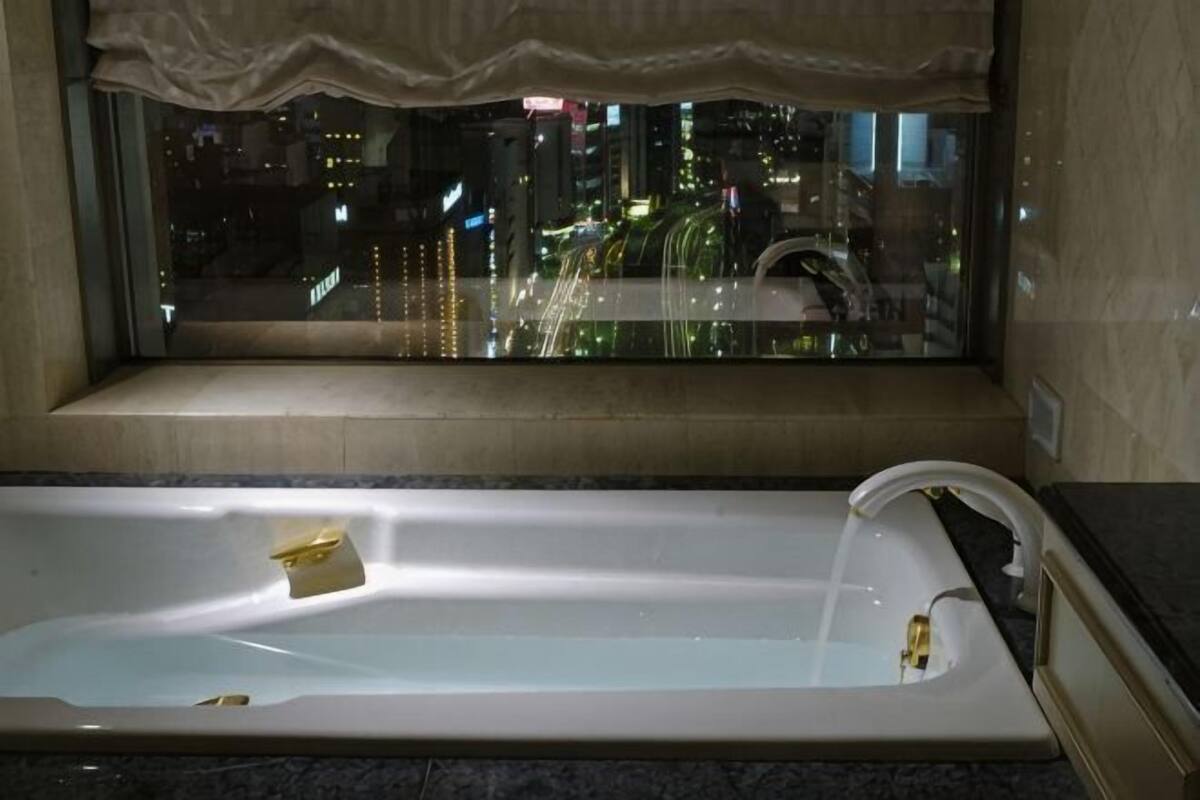 Una bañera con vista a un paisaje urbano nocturno a través de una ventana.