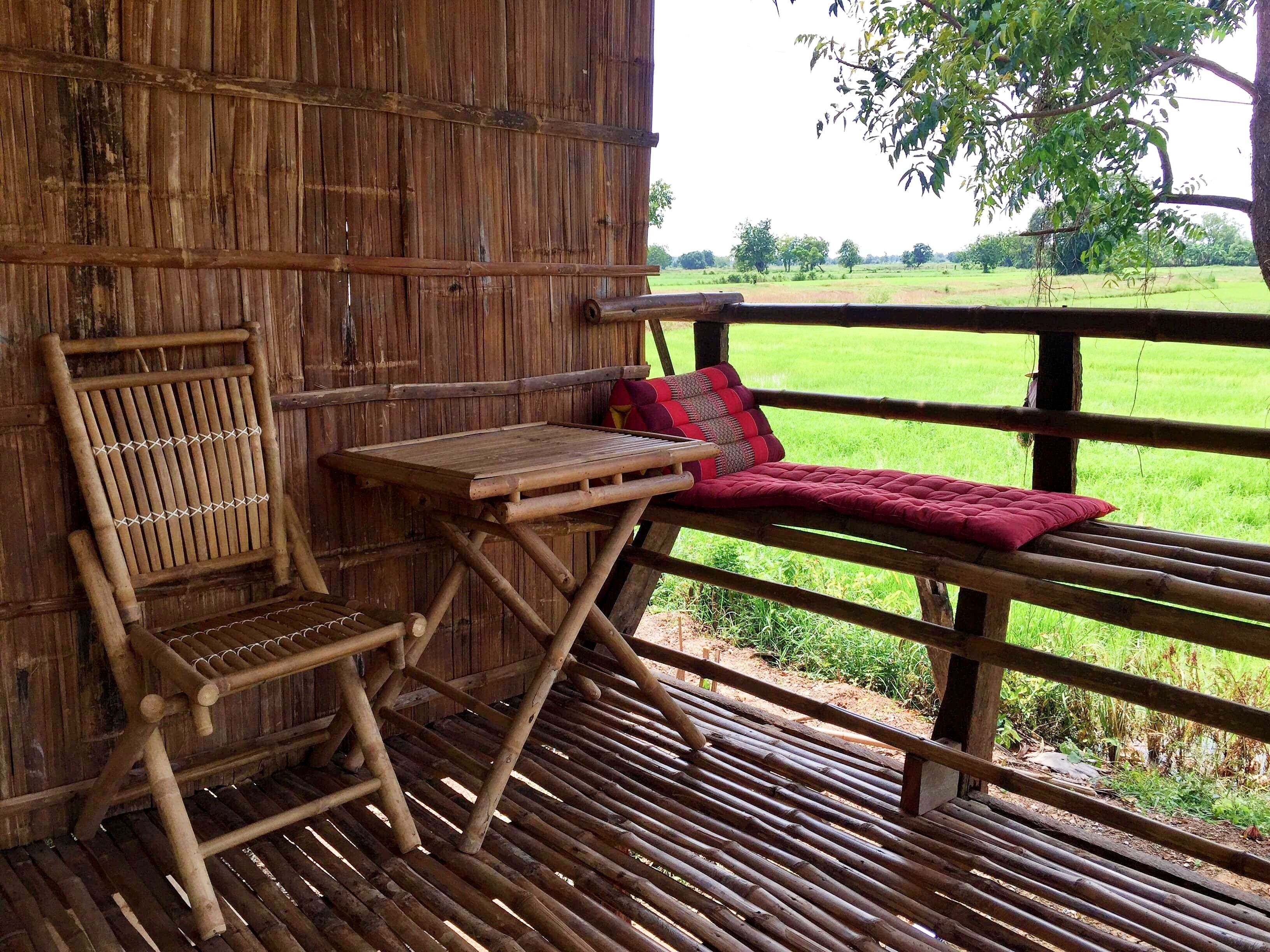 Une terrasse en bois rustique, agrémentée d’un banc et d’une table, qui offre une vue sur un champ verdoyant.