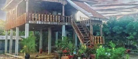 A wooden house with a balcony and a staircase leading to the upper floor.