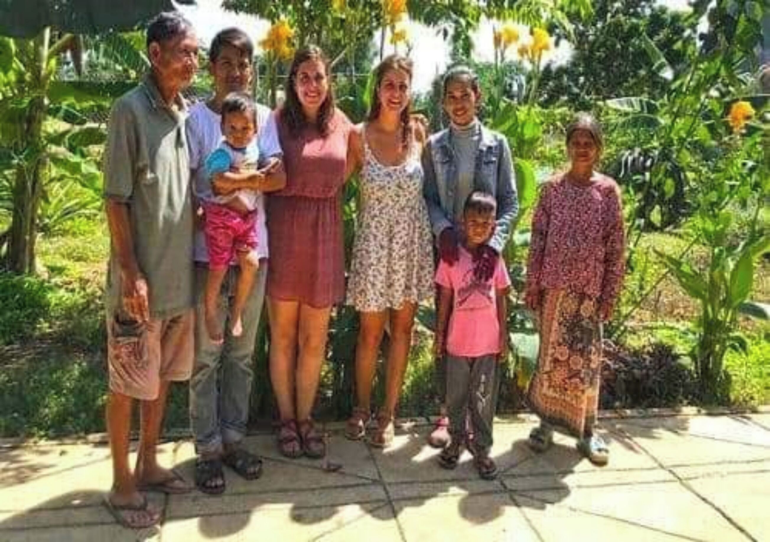 Un grupo de personas de pie en un patio con un jardín al fondo.