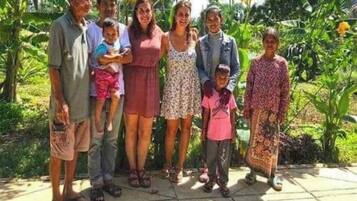Un grupo de personas de pie en un patio con un jardín al fondo.