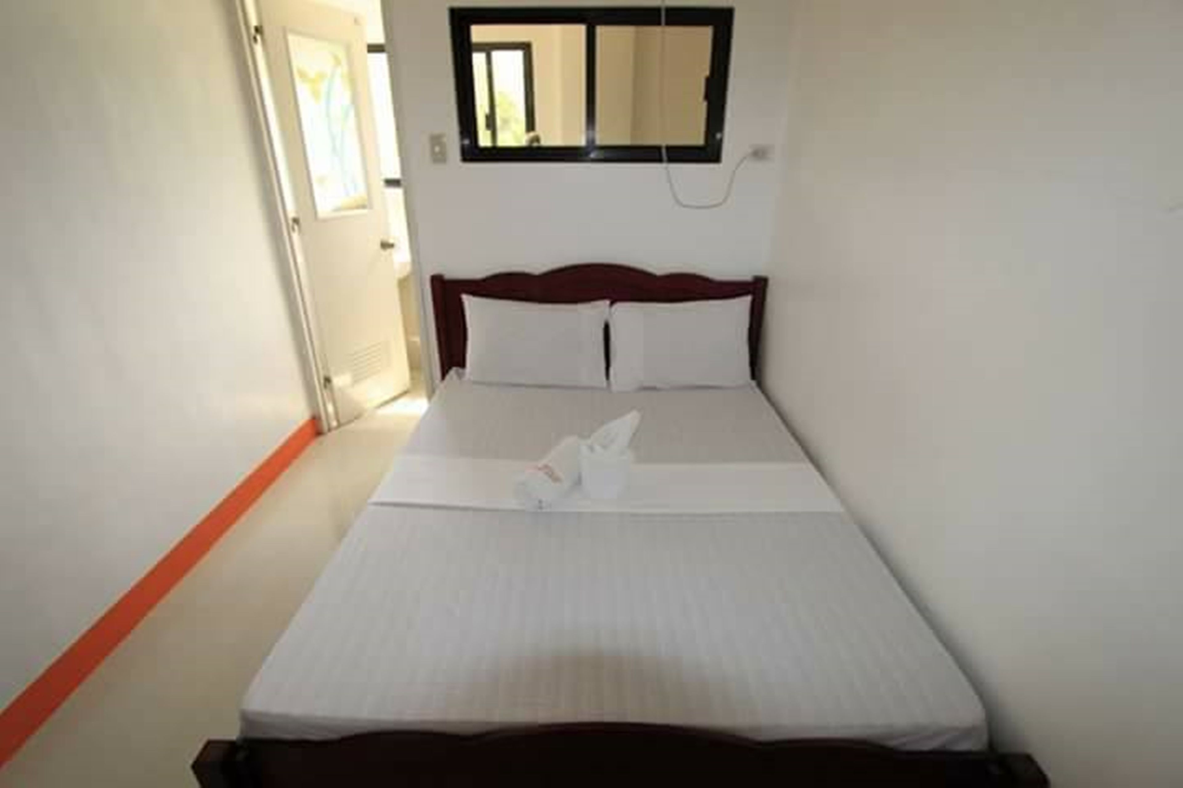 A hotel room with a bed, a window, and a door.