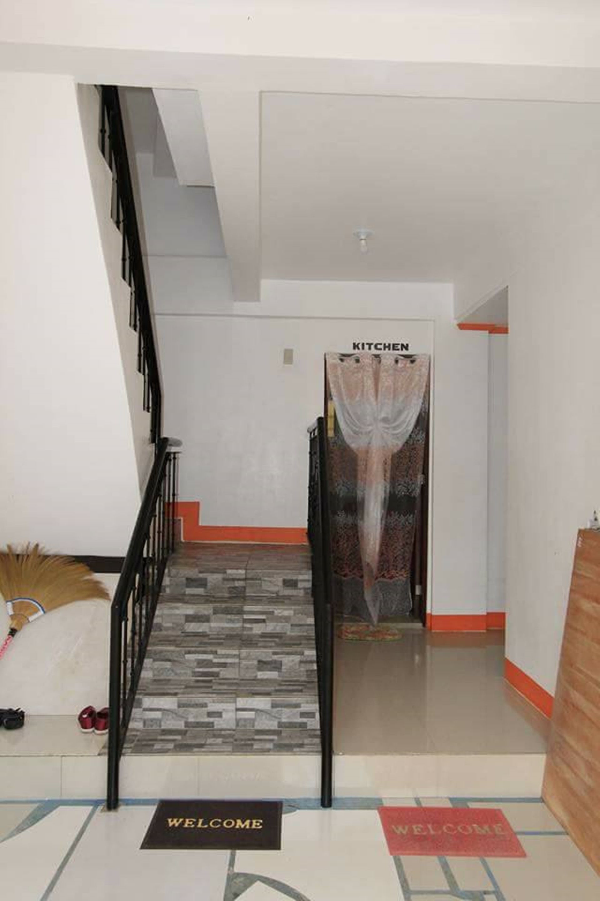 Eine Treppe führt zu einem Küchenbereich, am Fuß liegt eine Fußmatte mit der Aufschrift 'Welcome'.