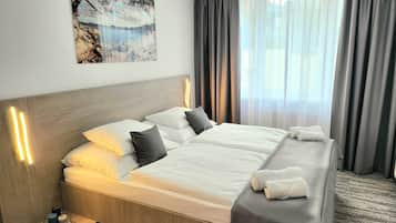 Habitación de hotel con cama doble, una mesita de noche con una vela y un cuadro en la pared.