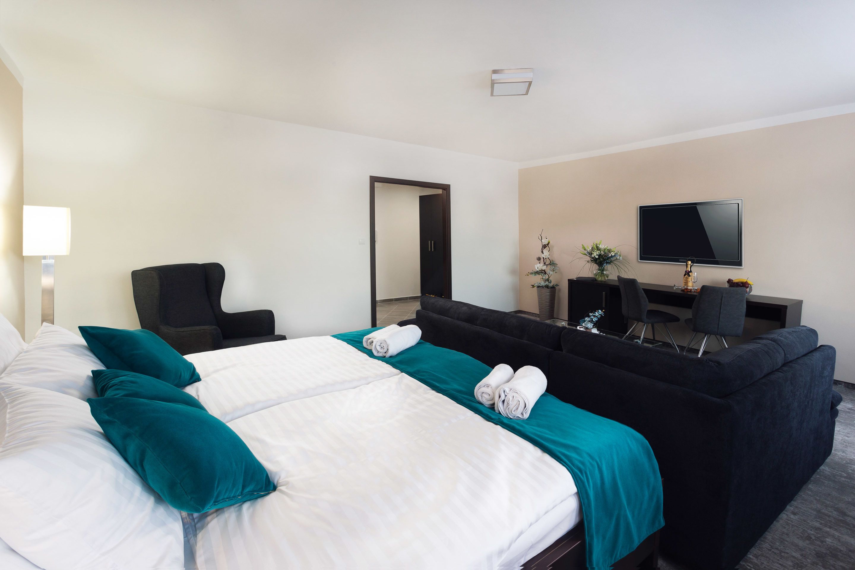 Una habitación de hotel con una cama grande, un sofá, un escritorio y un televisor.