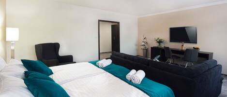 Una habitación de hotel con una cama grande, un sofá, un escritorio y un televisor.