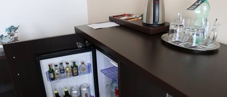 A compact refrigerator with a variety of beverages and a coffee maker on a counter.