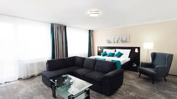 Une chambre d’hôtel comprenant un lit, un canapé, une chaise, une table basse en verre et une lampe.