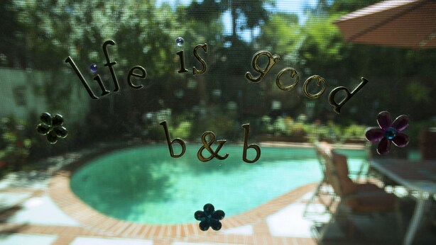 Et glasvindue med teksten "life is good" og dekorative detaljer.