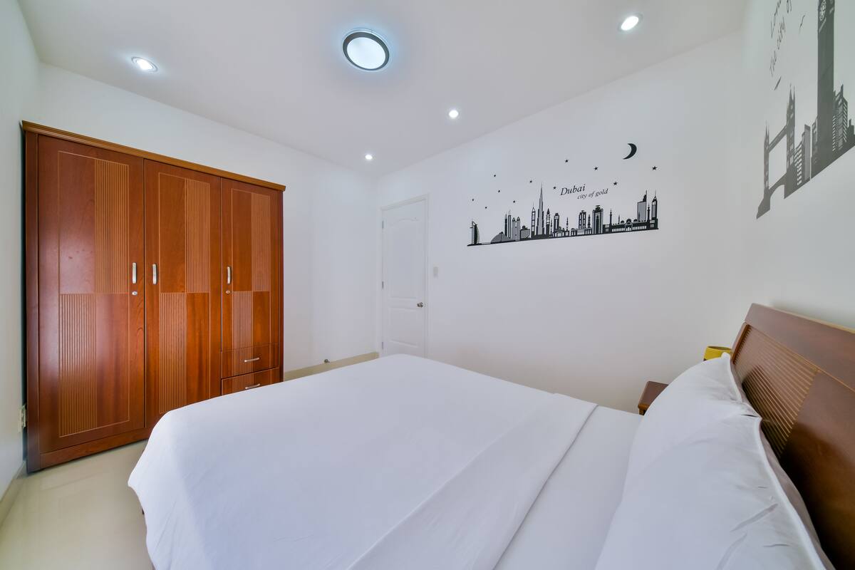 Une chambre avec un grand lit, une armoire en bois et un décor mural représentant le panorama de la ville.
