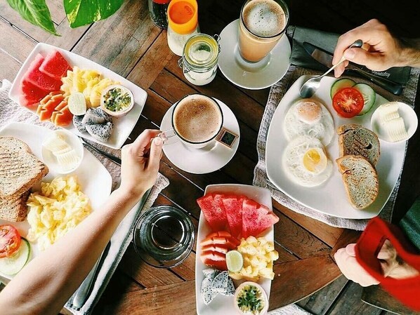 Desayuno servido en una mesa de madera, con diversos alimentos y bebidas.
