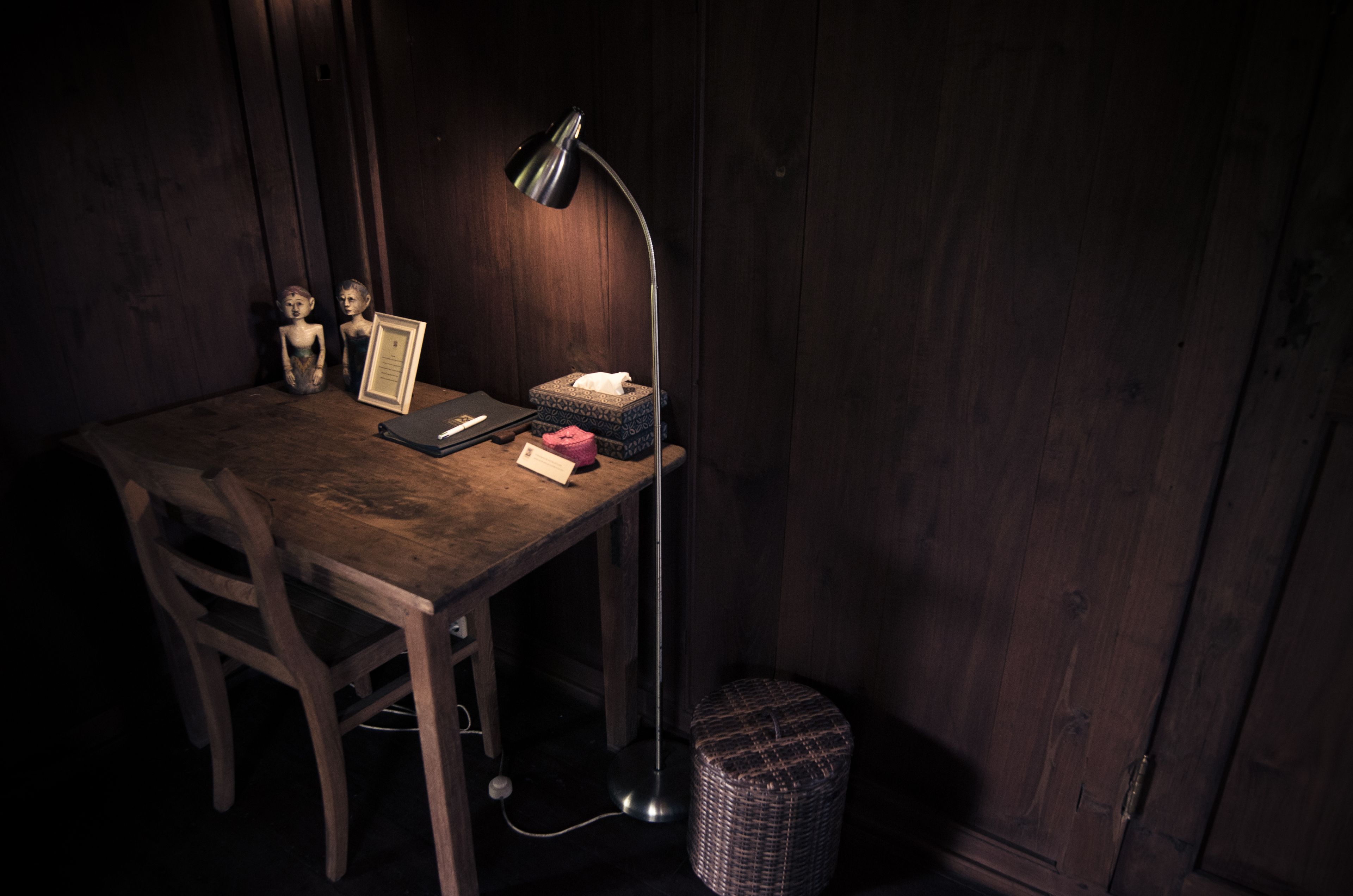 Ein Holztisch mit einem Laptop, einem gerahmten Bild, einer Lampe und einem kleinen Korb.