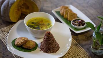 A plate with a bowl of soup, two fried items, and a cone-shaped rice dish, accompanied by a small bowl of sauce and a pumpkin.