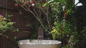 A large, freestanding bathtub in a garden setting with a wooden fence and lush greenery. - Yabbiekayu Eco Bungalows (Sewon)