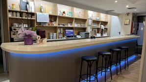 Een moderne bar met een gebogen toonbank, barstoelen en planken vol glazen en flessen.
