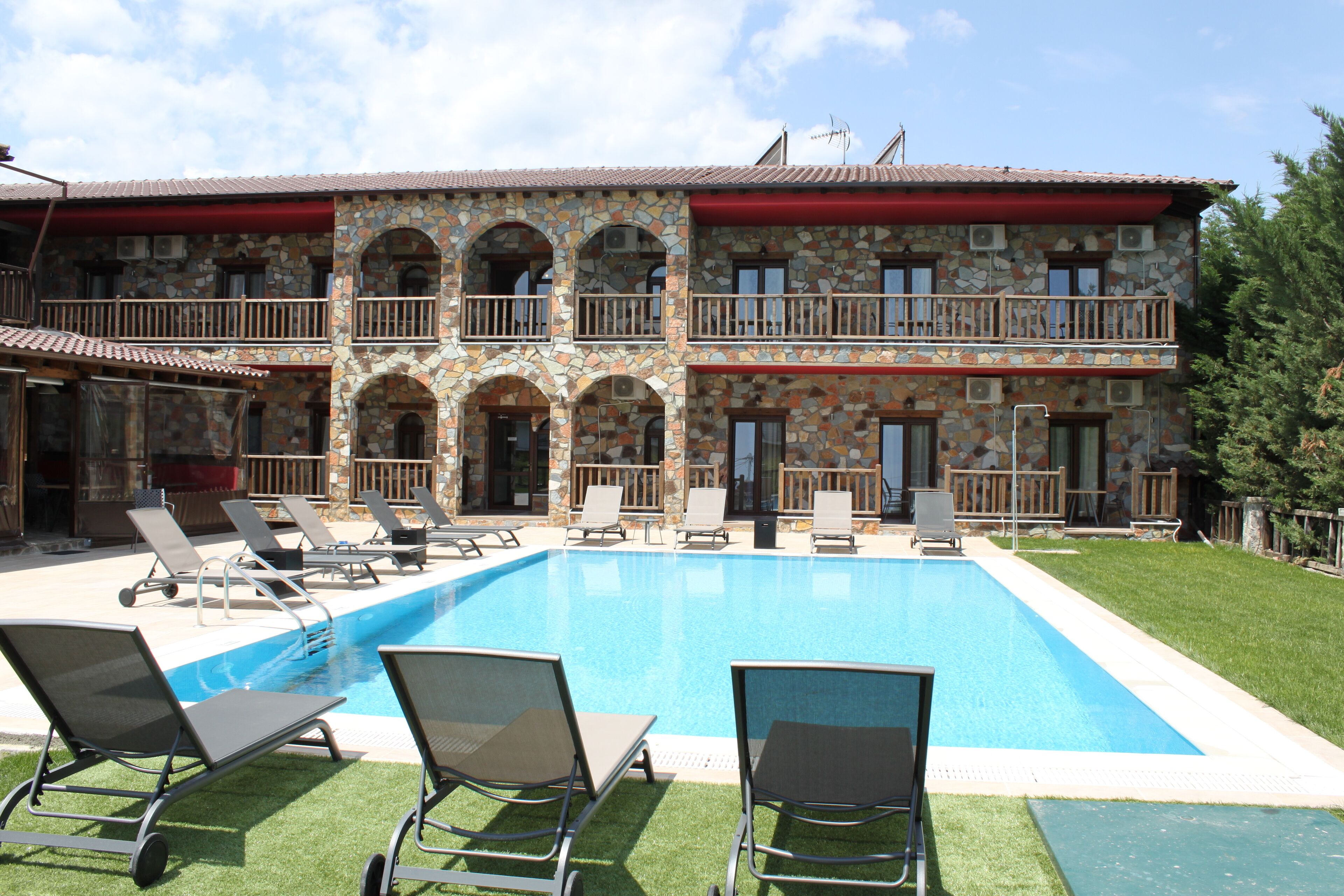 Ein Steinhaus mit Swimmingpool, Außenbereich und rotem Markisen