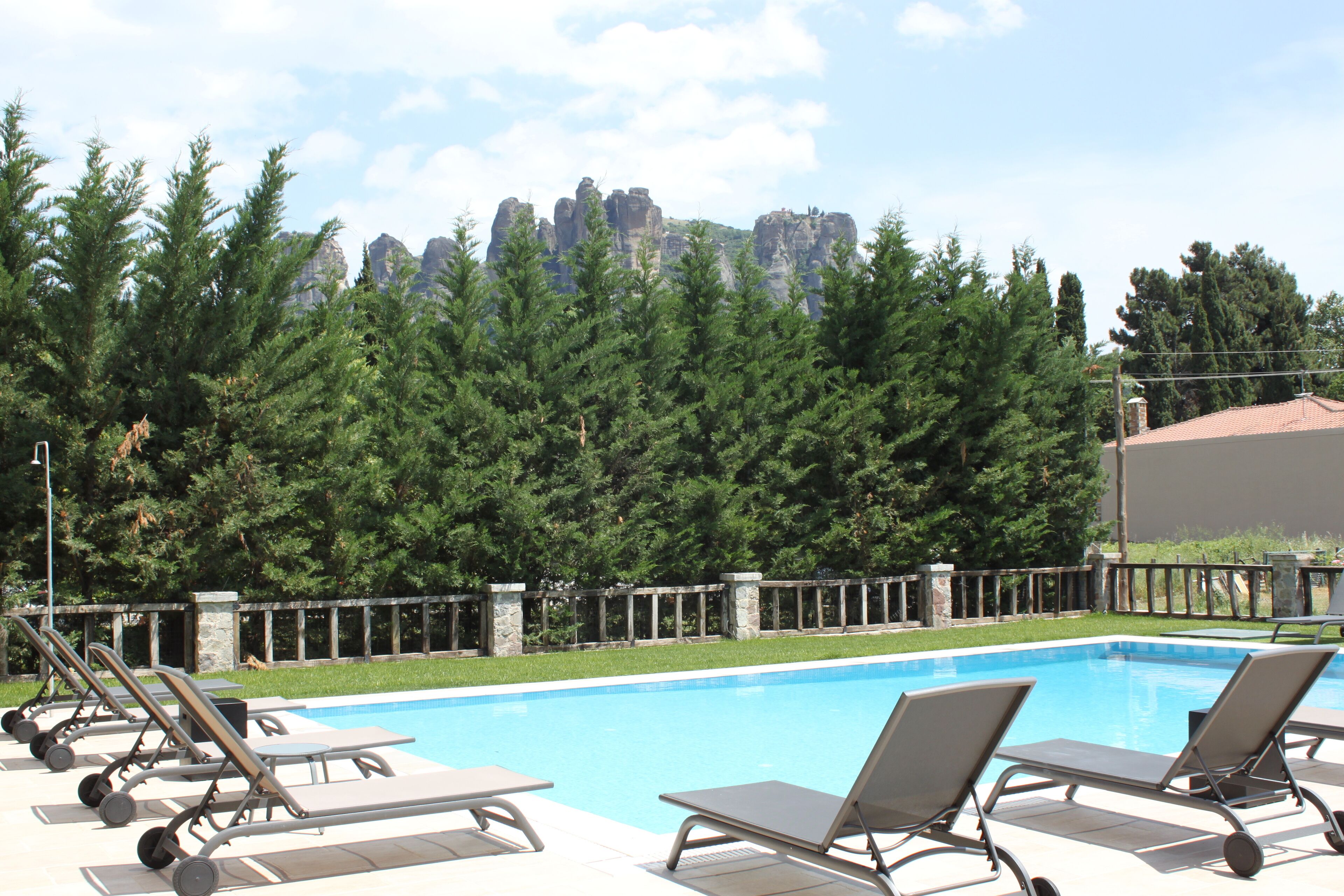Una piscina con sillones de descanso y un muro de piedra.